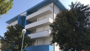 A multi-story building with a blue and white color scheme, featuring balconies and a clear sky. - Comfortable Flat Next to the Beach-beahost (San Michele al Tagliamento)