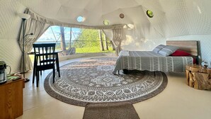 Een ruime, ronde kamer met een bed, een tafeltje en een stoel.