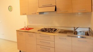 A kitchen with wooden cabinets, a gas stove, and a sink. - Lovely Flat Close to the Beach-beahost (San Michele al Tagliamento)