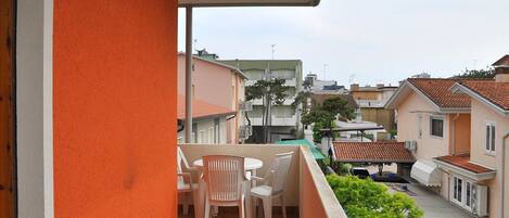 A balcony with a table and chairs, overlooking a residential area with houses and a clear sky.