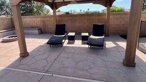 Eine überdachte Terrasse mit Liegestühlen und einer Pergola.