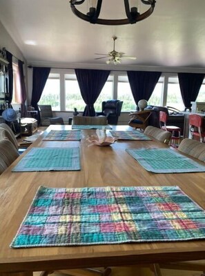 Enjoy meals in this inviting dining area with a long table, comfortable seating, and a window seat.