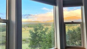 Una habitación con ventanas amplias que dan a un paisaje rural con árboles y colinas.