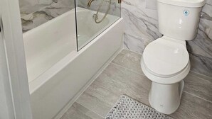 A modern bathroom with a glass-enclosed shower, a white bathtub, and a toilet. - Luxury Villa w/ pool wef/polo 5 min (Wellington)