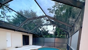 A covered swimming pool with a brick edge, surrounded by a white deck and a metal fence. - Luxury Villa w/ pool wef/polo 5 min (Wellington)