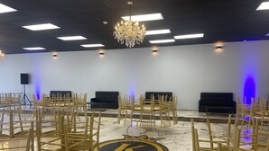 A spacious room with a marble floor, a chandelier, and multiple black sofas arranged in a semi-circle. - Amazing Event Space with Ample Parking  (Marietta)