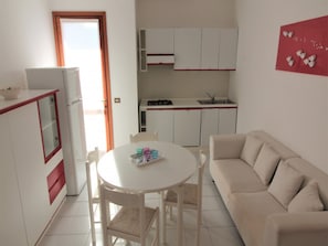 A compact living space with a kitchenette, a dining area, and a sofa.