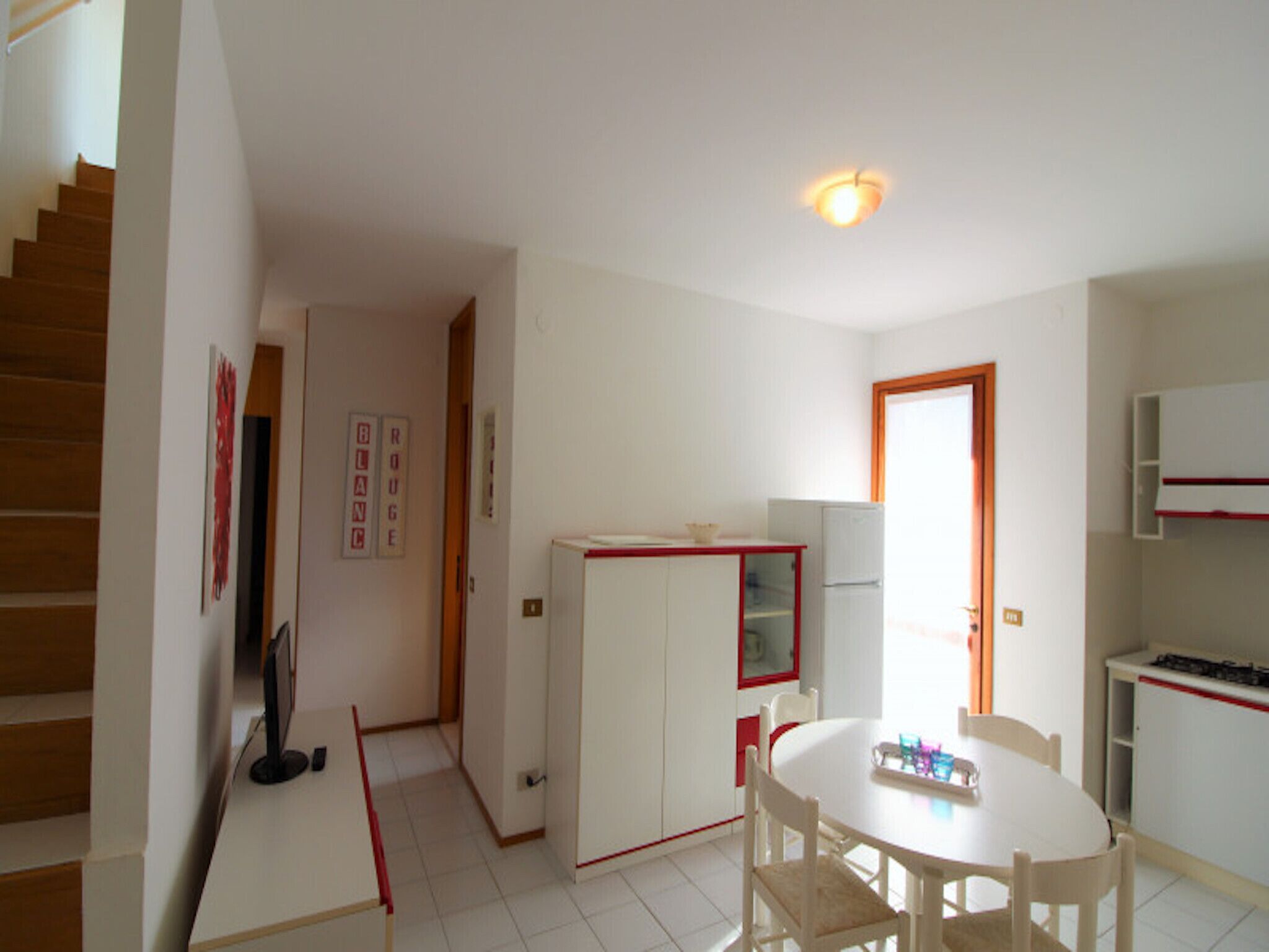 A kitchen with a dining table, chairs, a refrigerator, and a stove.