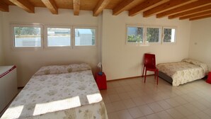A bedroom with two beds, a chair, and a window. - Attic Apartment 50mt From the Beach (Lignano Sabbiadoro)