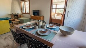 A dining area with a table set for four, a television, and a fireplace. - Plakakia Beachfront View (Aegina)