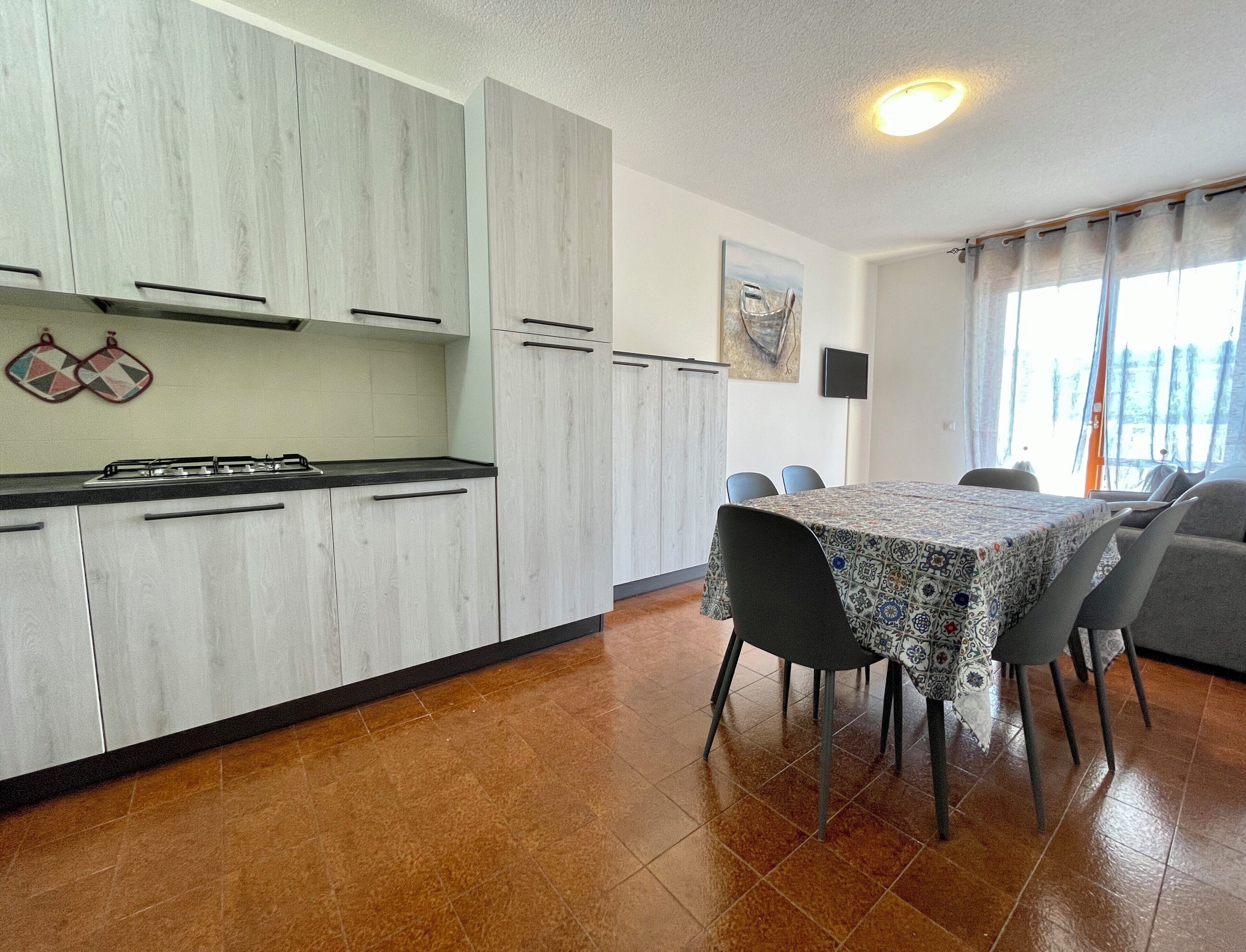 Una cocina con armarios blancos, una estufa a gas y un comedor con mesa y sillas.