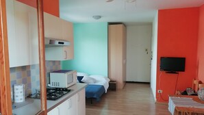 Una habitación compacta con kitchenette, una cama, televisor y comedor.