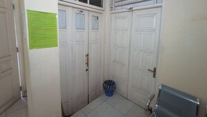 Un pasillo con dos puertas blancas, cada una con un número. Una cesta de ropa azul está apoyada en la pared.