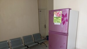 Un área de espera con un refrigerador, sillas y una puerta al fondo.