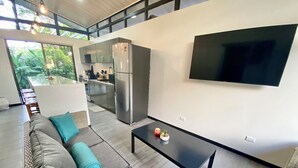 Ein modernes Wohnzimmer mit einer Couch, einem Couchtisch und einem an der Wand montierten Flachbildfernseher.