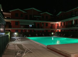 A swimming pool with lounge chairs and a building with balconies in the background.