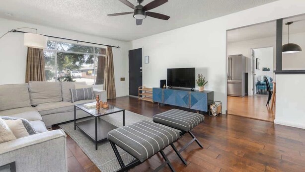 Ein modernes Wohnzimmer mit einer Couch, einem Hocker, einem Couchtisch und einem Fernseher auf einem blauen Schrank.