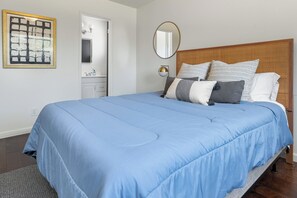 Quarto com cama grande, mesa de cabeceira, espelho e quadro na parede.