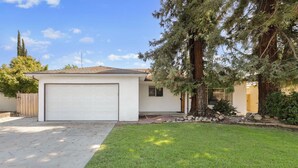 A residential house with a garage, a well-maintained lawn, and mature trees.