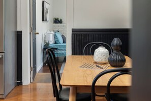 Un coin repas avec une table en bois, des chaises noires, un vase et un set de table à rayures.
