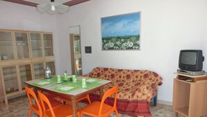 A dining area with a table, chairs, a cabinet, a sofa, and a television. - Wonderful Villa With Private Garden - Beahost (San Michele al Tagliamento)