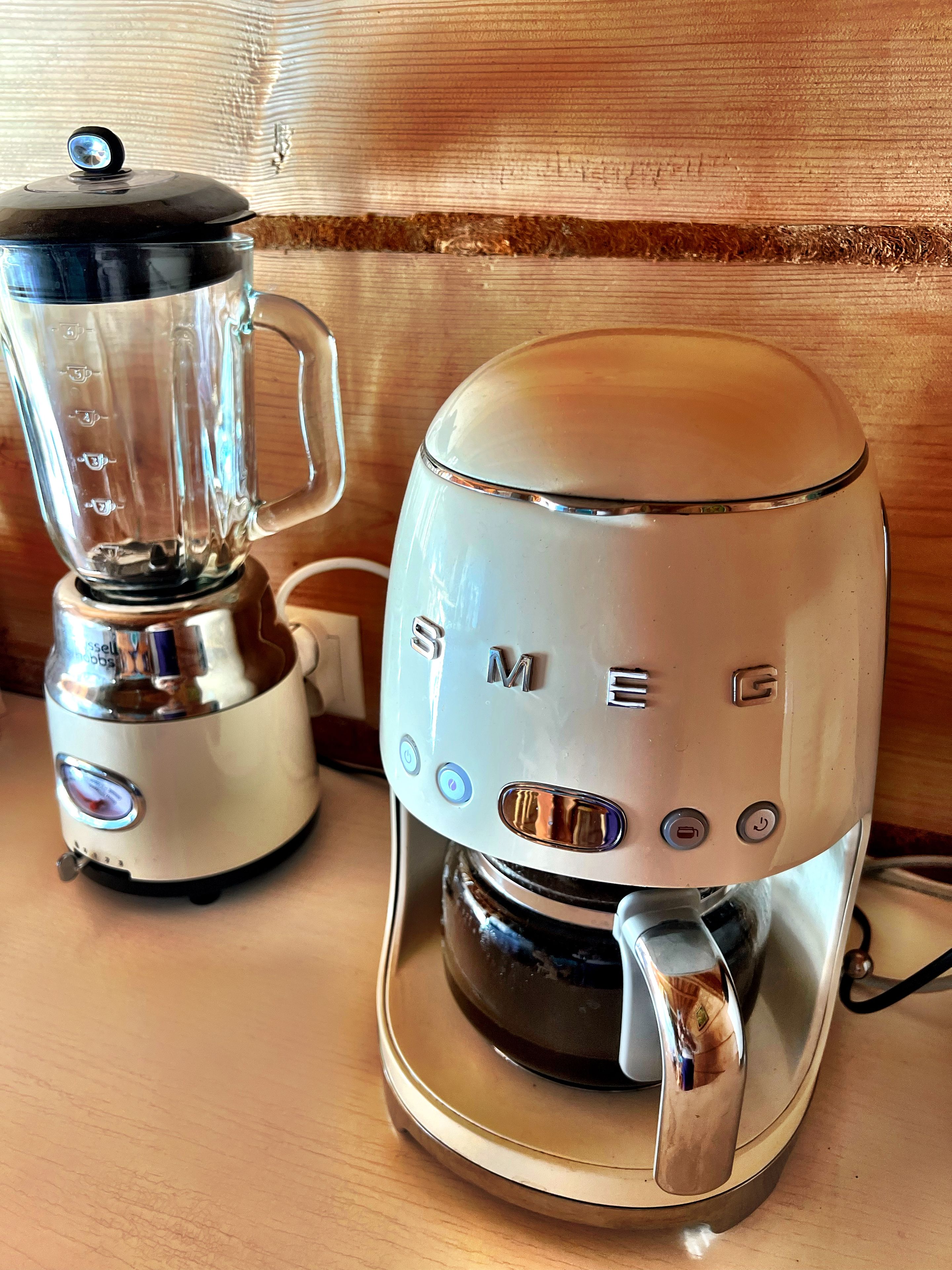 Une cuisine avec un mixeur et une machine à café posés sur un plan de travail en bois.