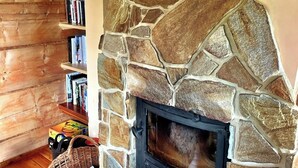 A stone fireplace with a bookshelf to the left.