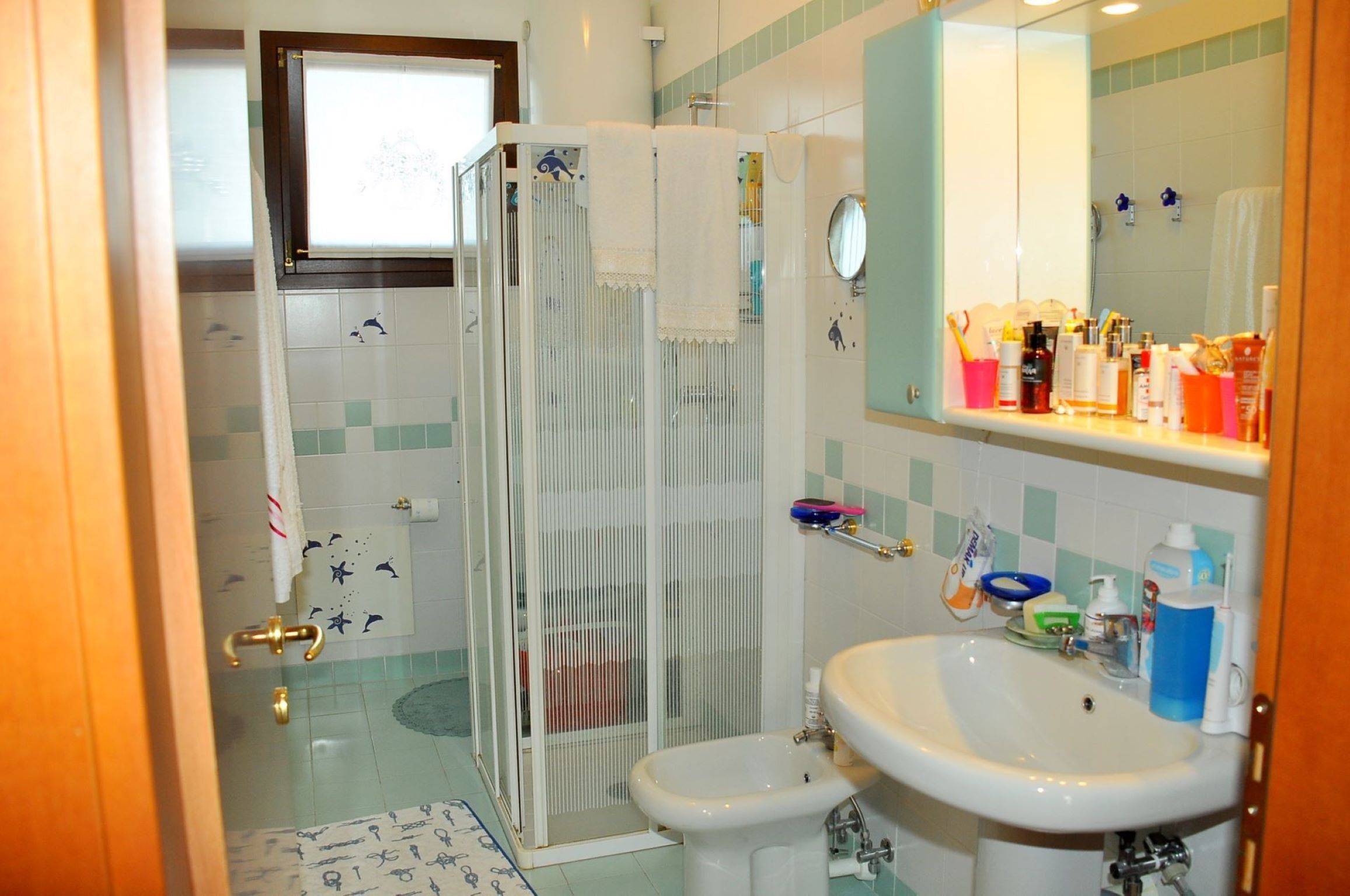 A bathroom with a shower enclosure, a sink, and a mirror.