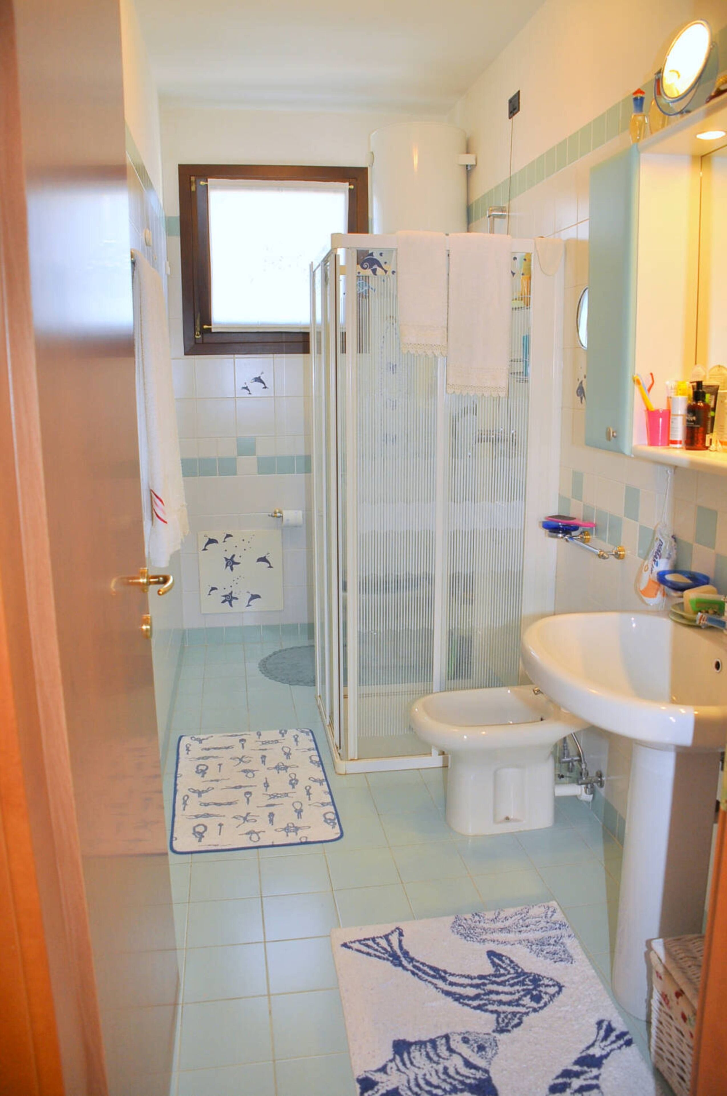 A bathroom with a shower, toilet, sink, and a window.