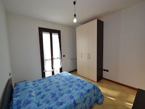 A bedroom with a bed, a wardrobe, and a radiator. - Comfortable Beachfront Apartment (Rosolina)