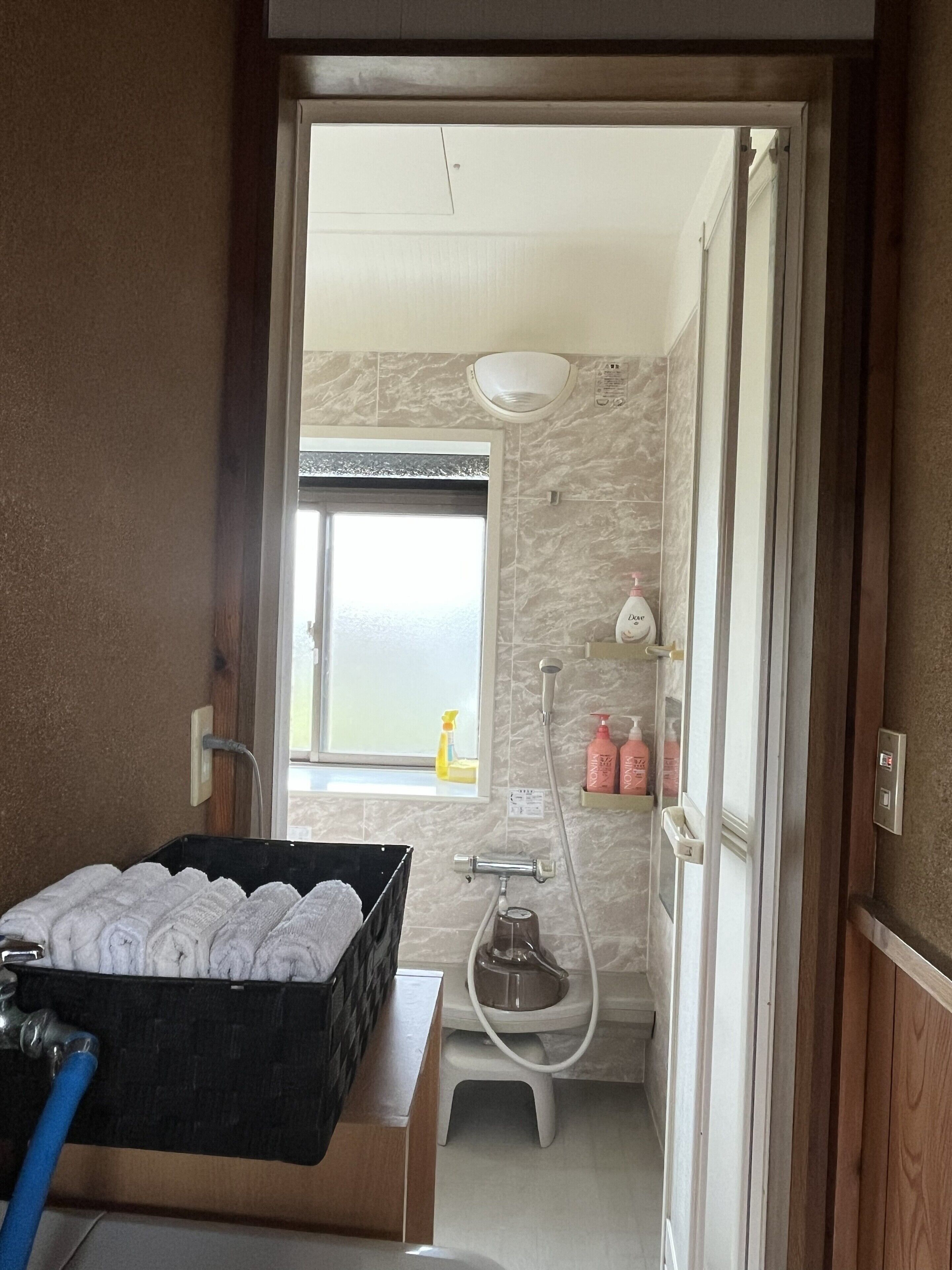 Une salle de bain avec une douche, un lavabo, un porte-serviettes et une fenêtre.