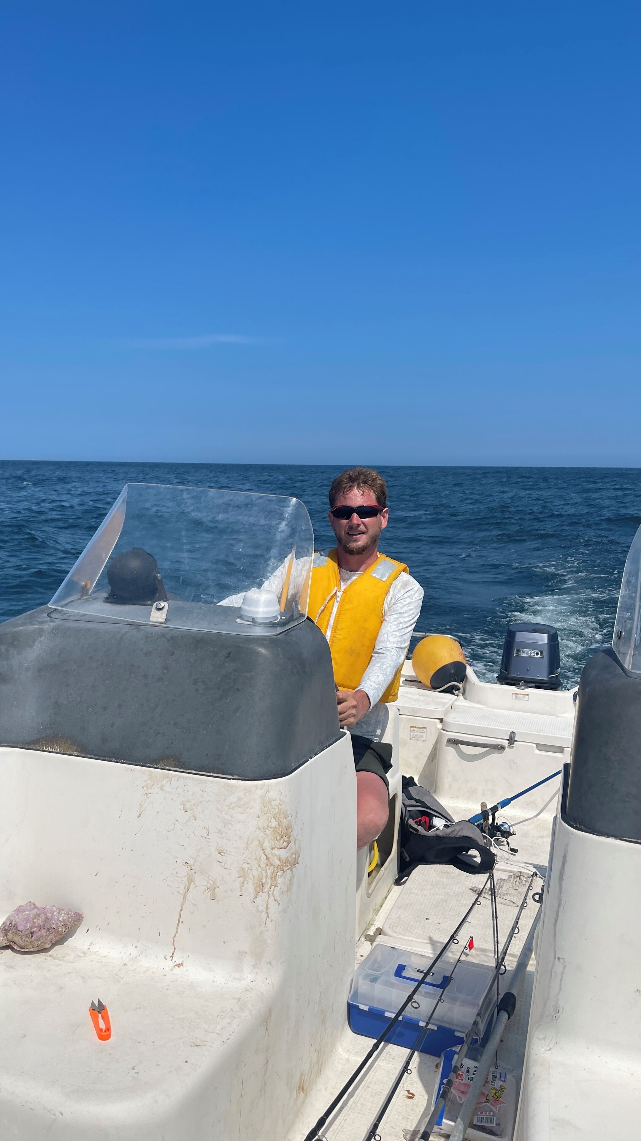 A man on a boat with fishing equipment and a clear view of the ocean.