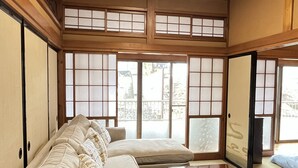 Une pièce de style japonais traditionnel, avec un sol recouvert de tatamis, une basse table en bois et un canapé agrémenté de coussins.