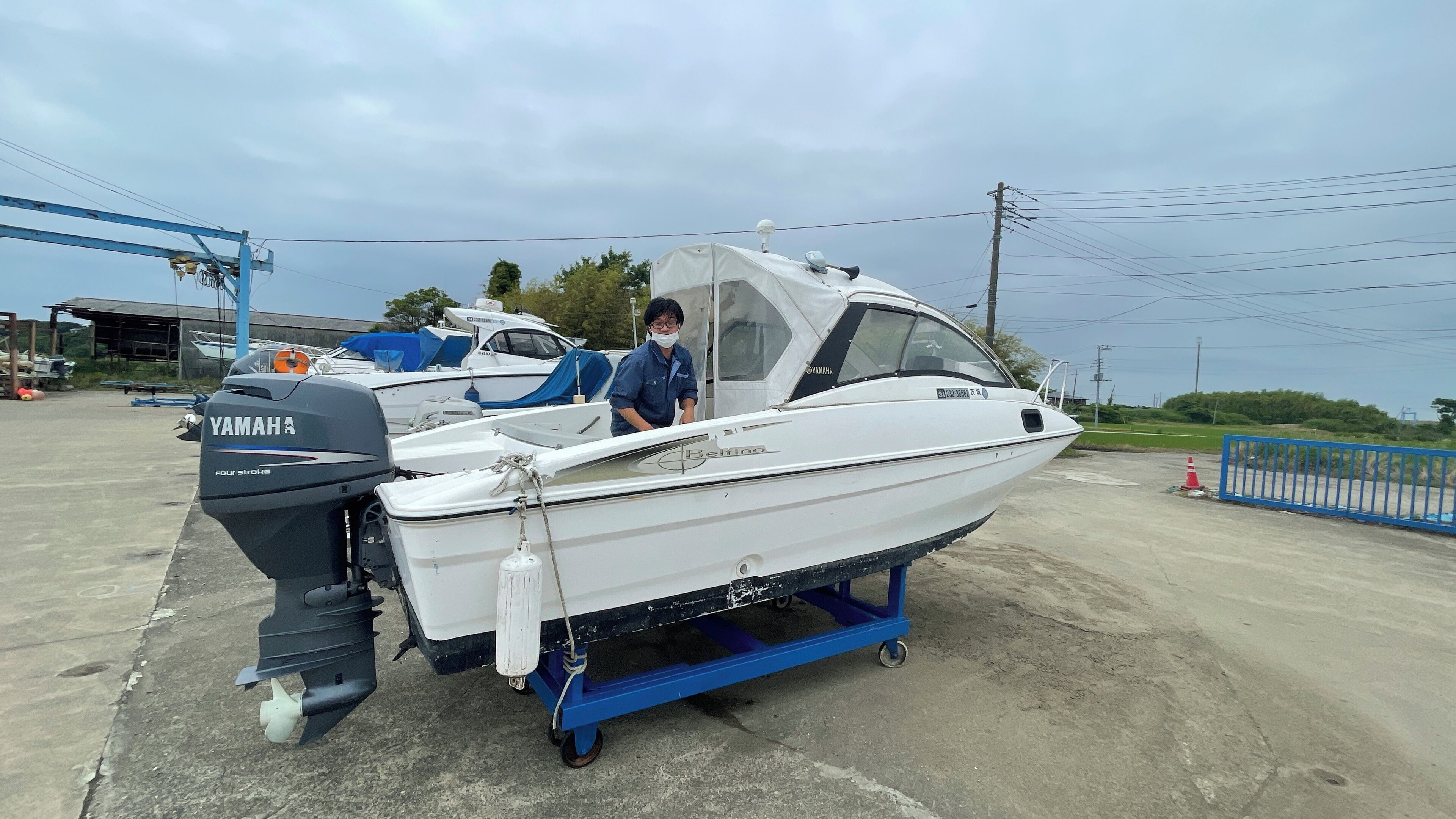 A white boat with a Yamaha outboard motor on a trailer, parked on a concrete surface.