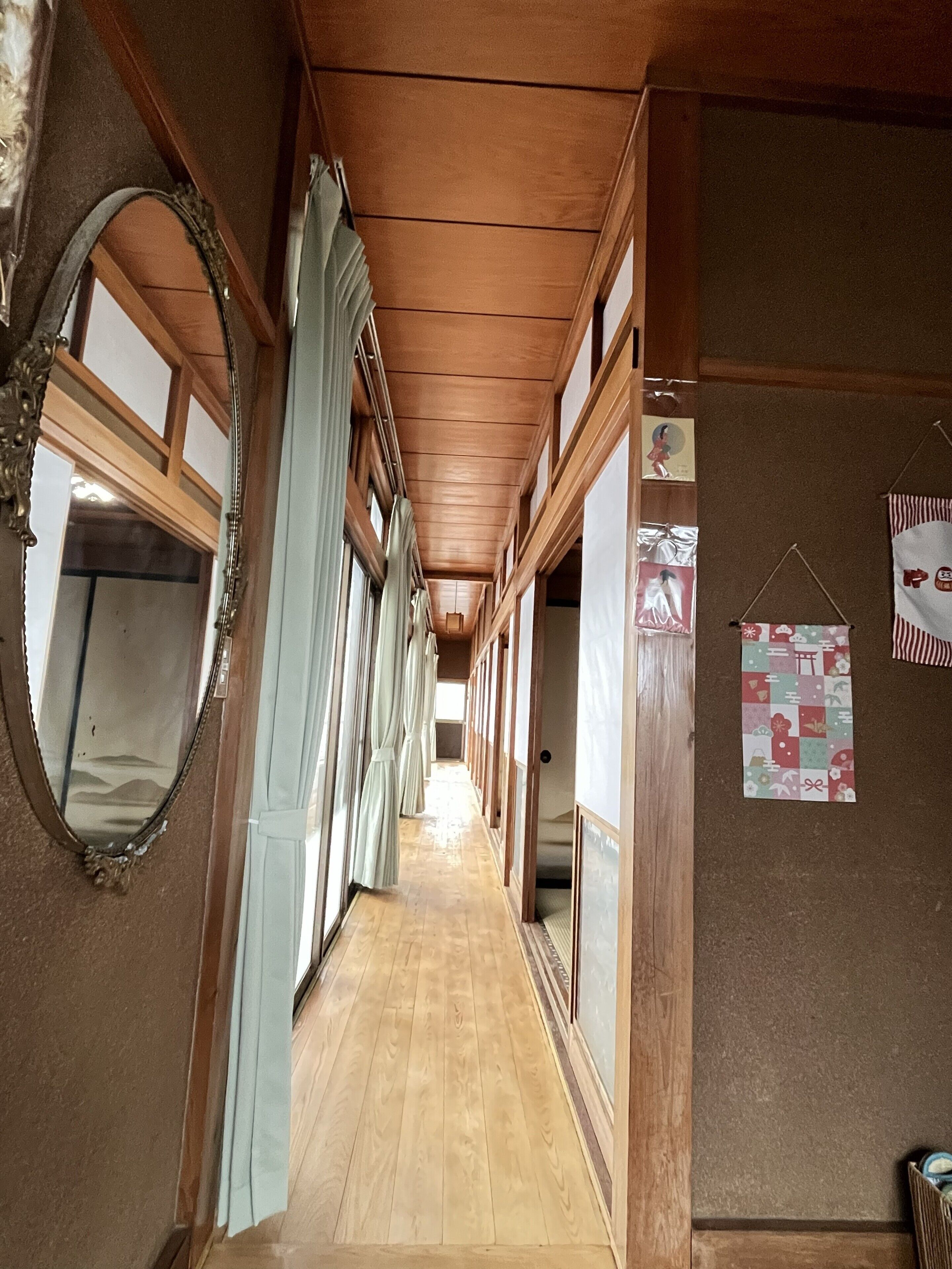 Un pasillo con suelo de madera, un espejo y una pared con un cartel.