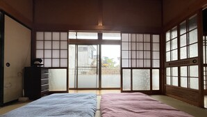 Une pièce de style japonais traditionnel, avec un sol recouvert de tatamis, des portes coulissantes et un lit doté de draps à motifs.