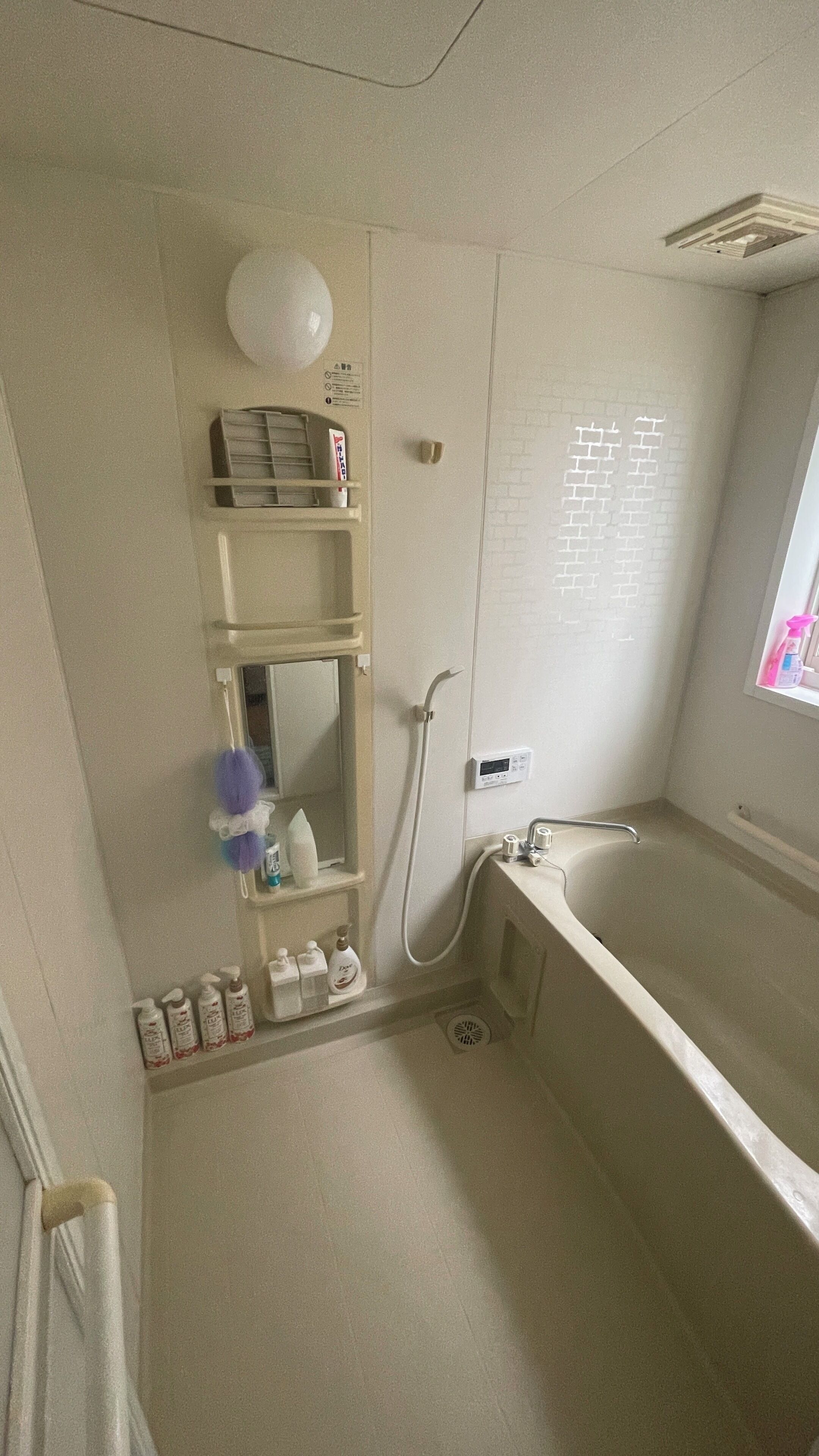 A bathroom with a bathtub, a shower, a mirror, and shelves with toiletries.