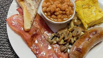 Um prato com torradas, feijão, bacon, cogumelos, salsichas e ovo frito.