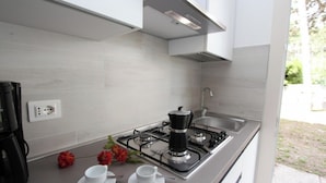 Uma cozinha moderna com fogão a gás, cafeteira e pia.