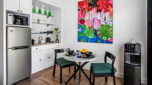 A modern kitchen with white cabinets, a stainless steel refrigerator, and a dining area with a round table and chairs. - Villa Balik II Seminyak (Seminyak)