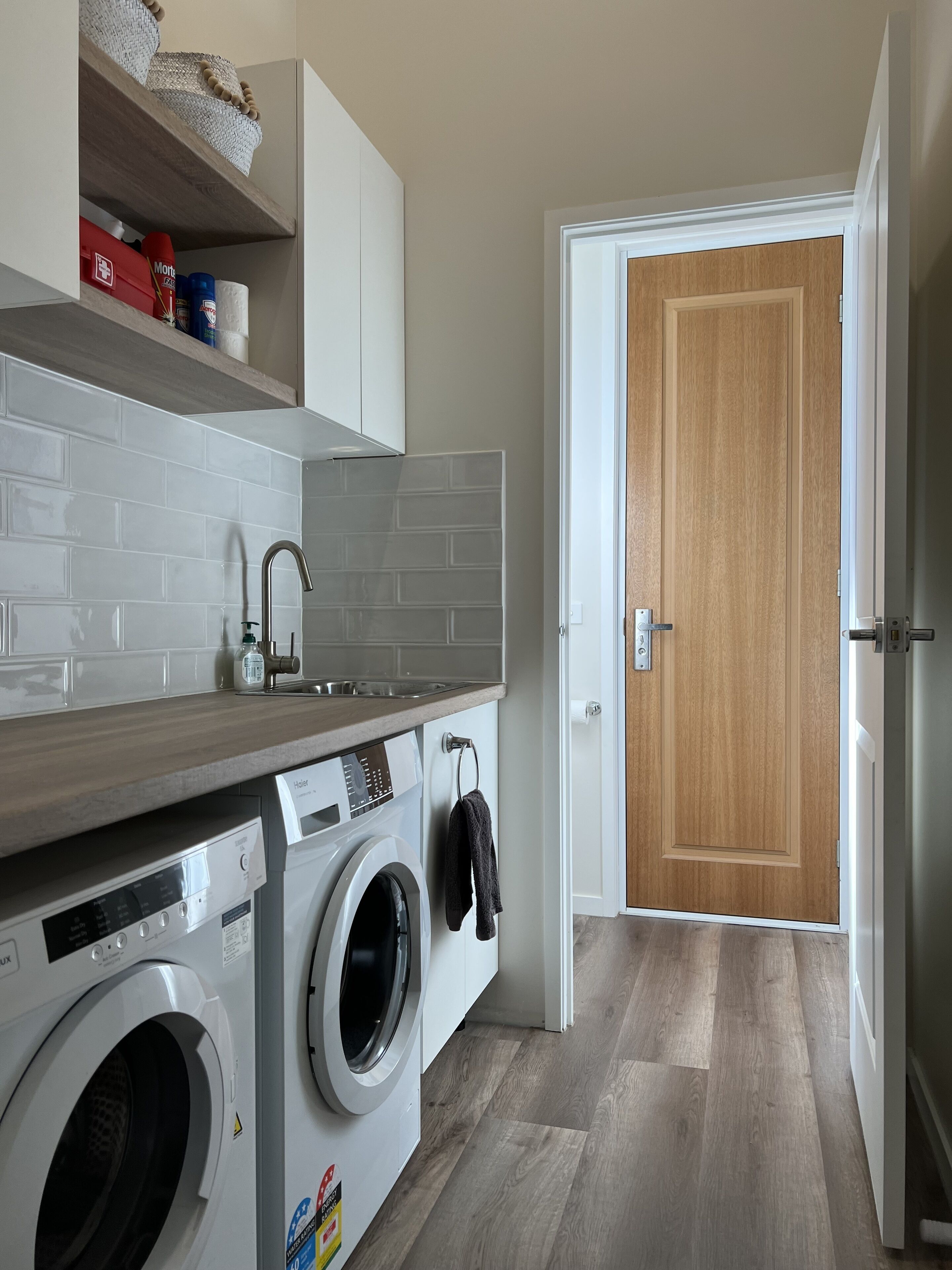 Une petite cuisine équipée d’un lave-linge, d’un évier et d’une porte en bois.