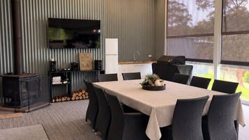 Un espace repas moderne comprenant une grande table, des chaises, un téléviseur et une cheminée.