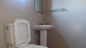 Casa de banho com sanita, lavatório e espelho.