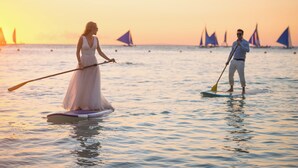 Zwei Personen stehen auf Paddleboards auf ruhigem Wasser bei Sonnenuntergang.