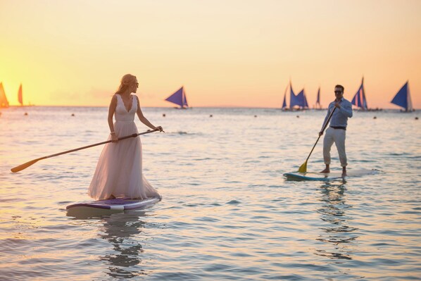 Two people paddleboarding on a calm sea during sunset. - Boracay Sea View Hotel (Boracay Island)