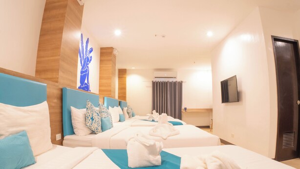 Ein Hotelzimmer mit zwei Betten, einem Flachbildfernseher und einer Wand mit Holzvertäfelung.