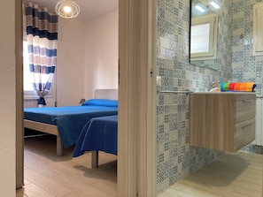 Une chambre d’hôtel avec deux lits, une salle de bain avec un miroir et un plancher en bois.