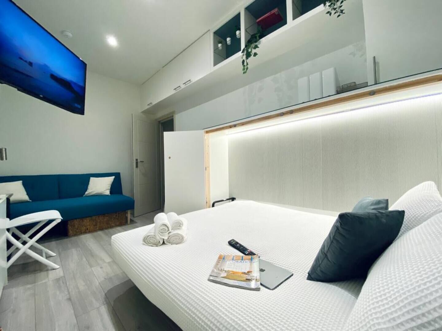 Een moderne hotelkamer met een groot bed, een blauwe bank en een flatscreen televisie aan de muur.