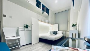Een moderne hotelkamer met een bed, een bureau, een stoel en een glazen tafel.