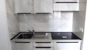 A compact kitchen with white cabinets, a sink, and a stove. - Minimalist Apartment in a Quiet Area - Beahost (San Michele al Tagliamento)